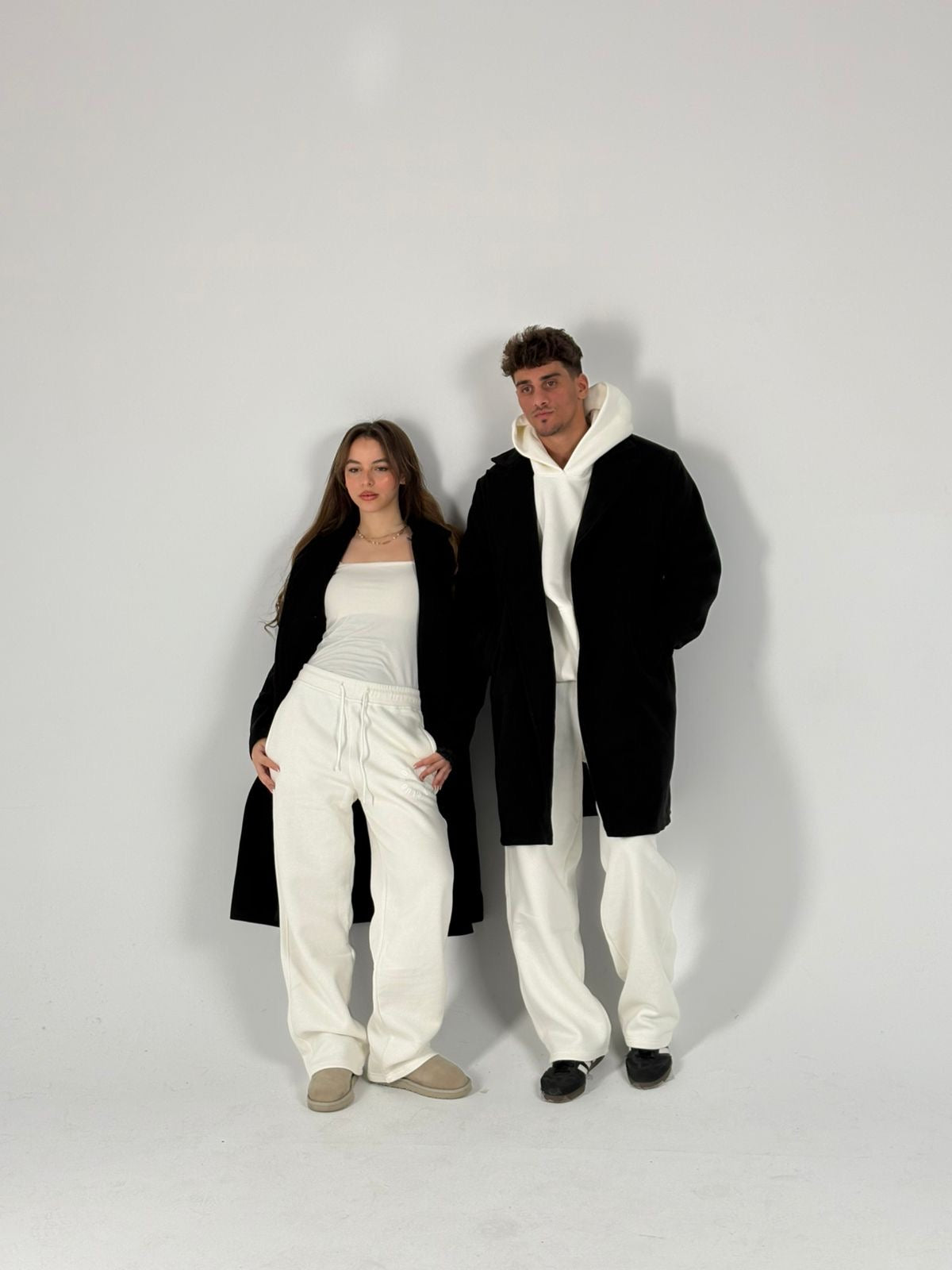 2 models are wearing oversized coats relaying with hoodies and relaxed-fit sweatpants 